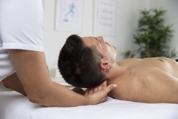 female-physiotherapist-massaging-male-patient-office